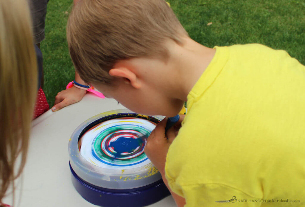 boy adding paint to spin art machine