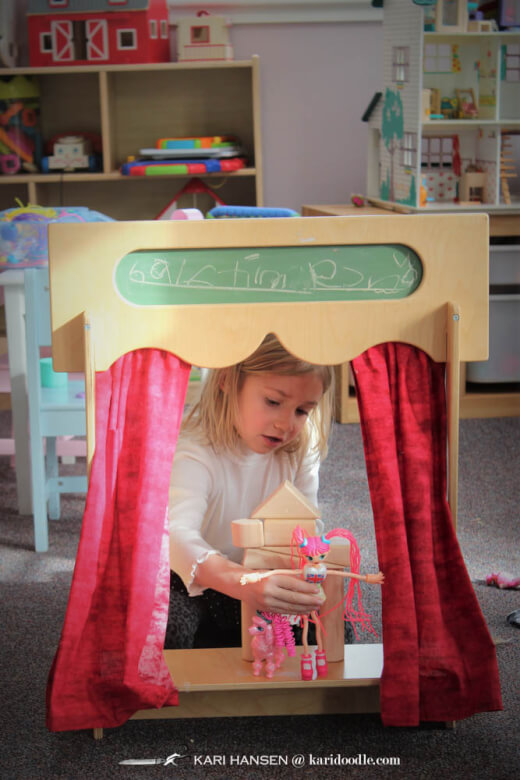 little girl playing in puppet theater
