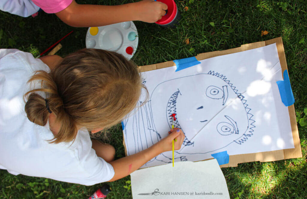 child painting her drawing of a face