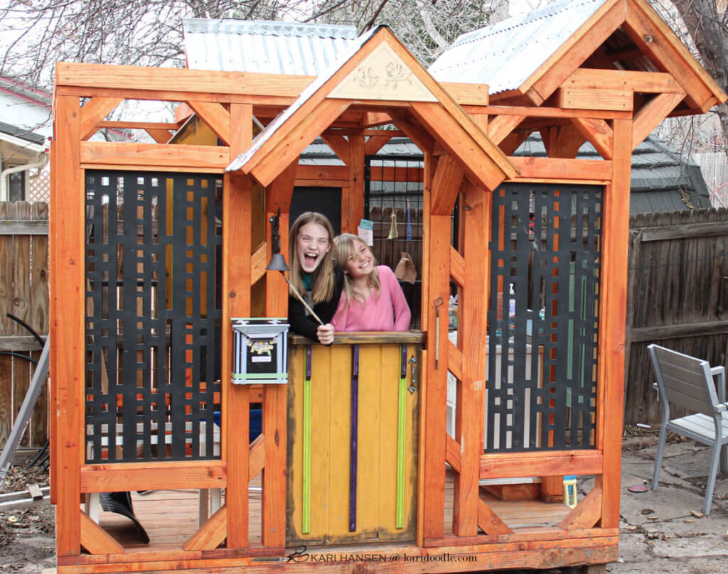 2 girls looking out of playhouse dutch door